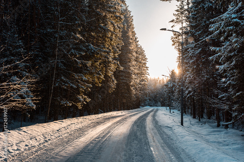 Winter Landscape with road trough snow covered trees at sunset