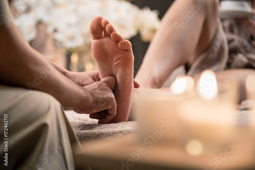 Woman enjoyingreflexology foot massage in wellness spa photo