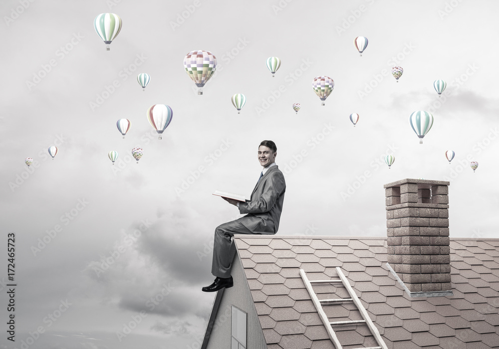 Man on roof reading book and aerostats flying in air Man on roof reading book and aerostats flying in air