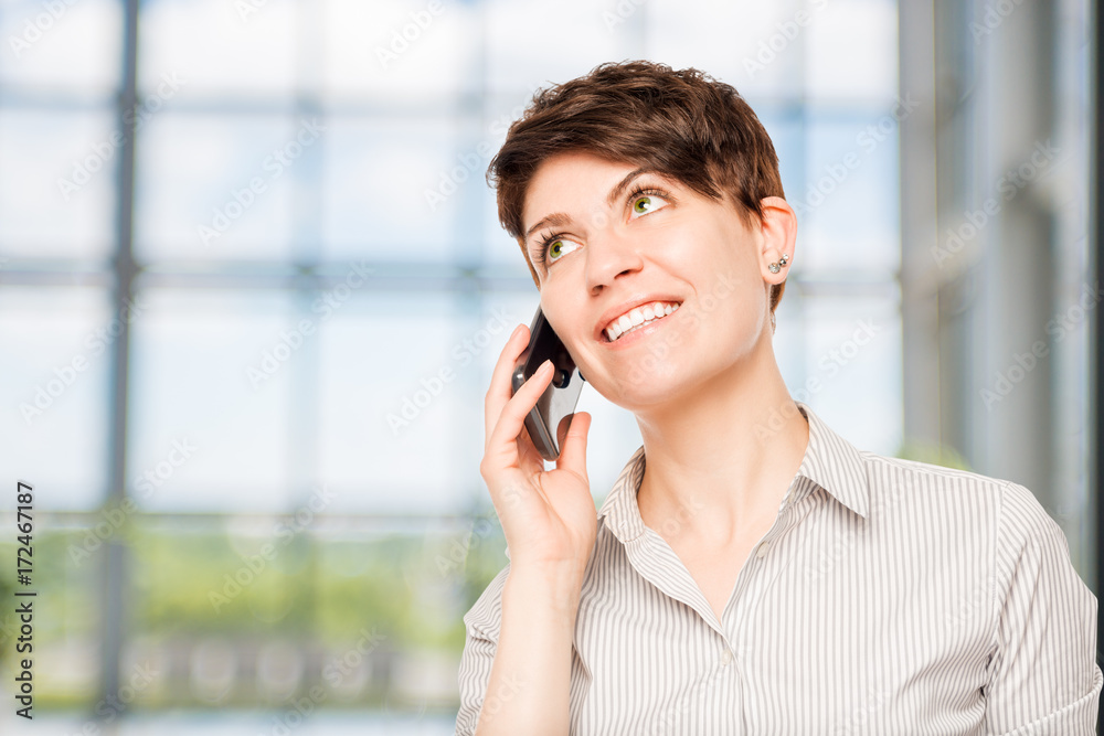 smiling woman talking on a mobile phone in the office smiling woman talking on a mobile phone in the office