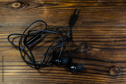 Black earphones on wooden table. Top view