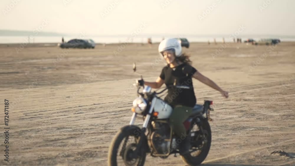 beautiful young woman motorcyclist rides an old cafe racer motorcycle and dances on it beautiful young woman motorcyclist rides an old cafe racer motorcycle and dances on it