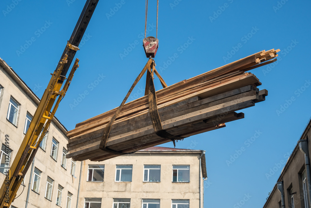 Crane lifts wooden slats on the roof, blue sky Crane lifts wooden slats on the roof, blue sky