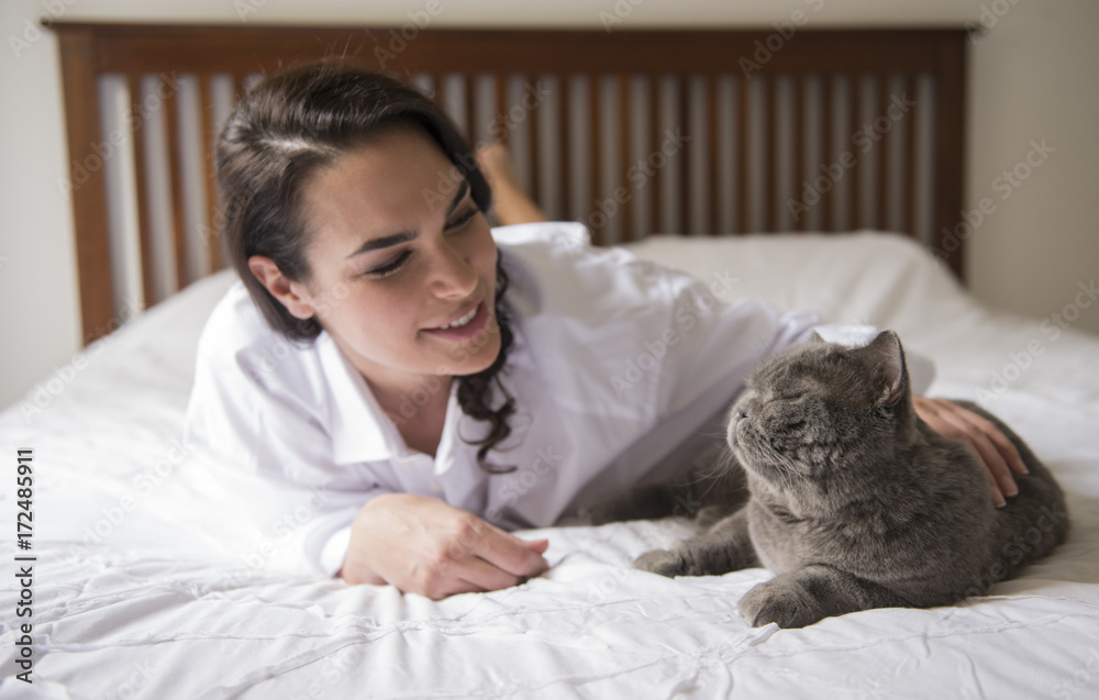 Woman lying on a bed with a grey cat Woman lying on a bed with a grey cat