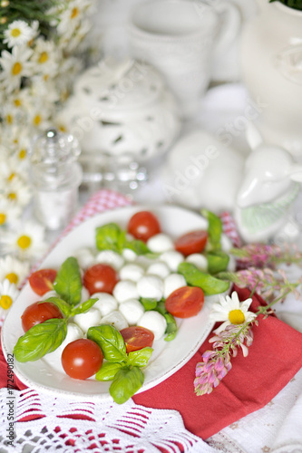 salad with caprese. Italian cuisine. classical italian recipes. ceramic tableware. In white colors