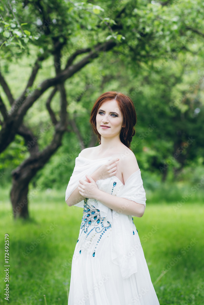 Woman in long white dress in summer garden Woman in long white dress in summer garden