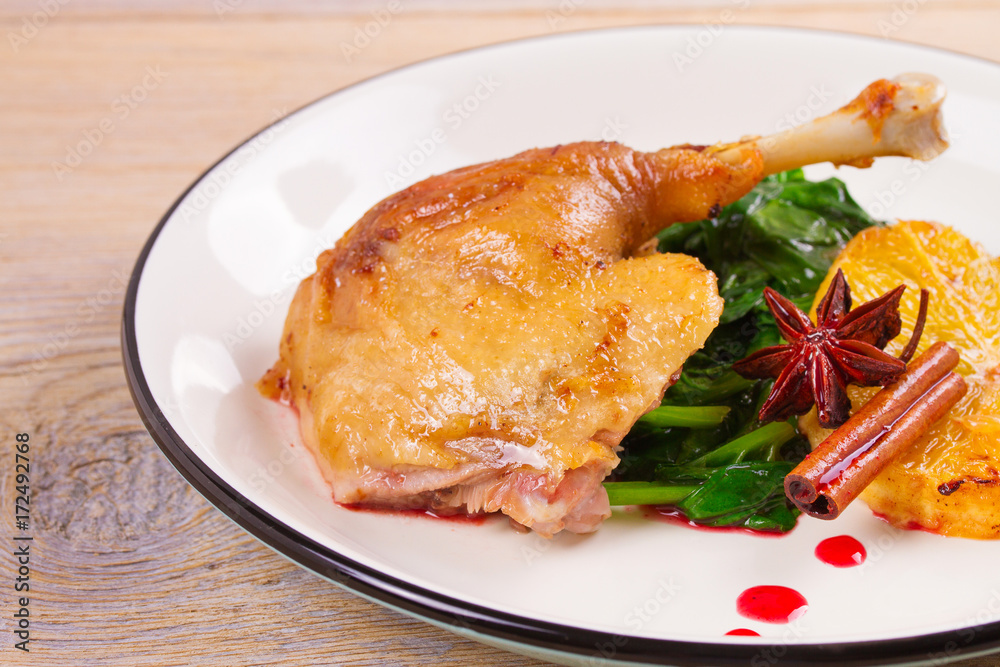 Duck leg with spinach, orange and spices: cinnamon and star anise in red wine sauce, horizontal Duck leg with spinach, orange and spices: cinnamon and star anise in red wine sauce, horizontal