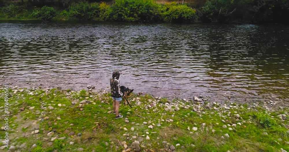 A girl plays stick with her dog in the river - aerial traveling A girl plays stick with her dog in the river - aerial traveling