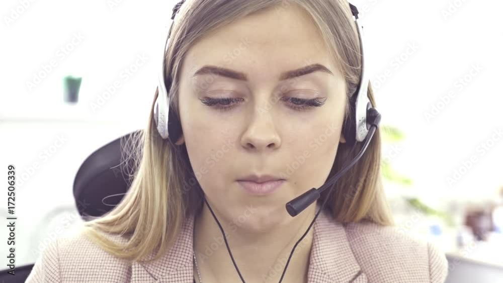 The operator of the hotline with headsets, sit at the computer in the office and advise clients. Workers call-center, a woman talking to customers. She prints on the computer and answers questions. The operator of the hotline with headsets, sit at the computer in the office and advise clients. Workers call-center, a woman talking to customers. She prints on the computer and answers questions.