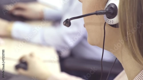 The operator of the hotline with headsets, sit at the computer in the office and advise clients. Workers call-center, a woman talking to customers. She prints on the computer and answers questions.