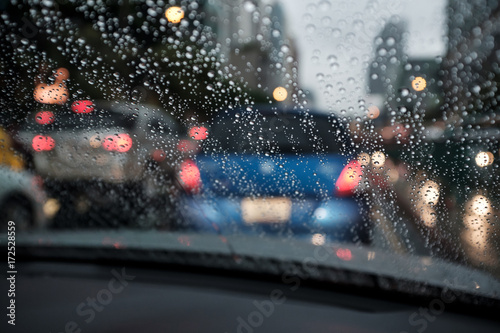 abstract rain droplets on car windshield with bokeh of traffc at twilight for background, shallow depth of field photo