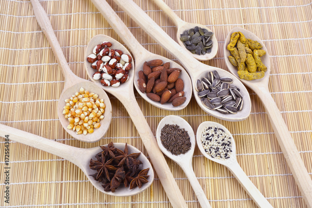 Wooden spoons group on mat with healthy seeds, nuts and spices