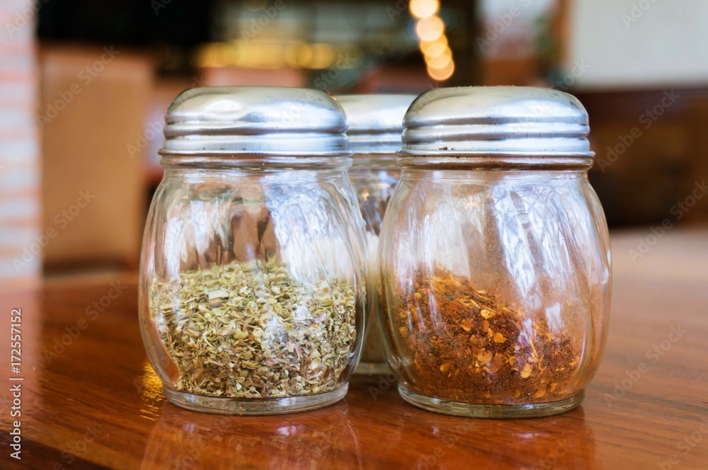 Glass of cheese salt and pepper shakers on wooden table in restaurant