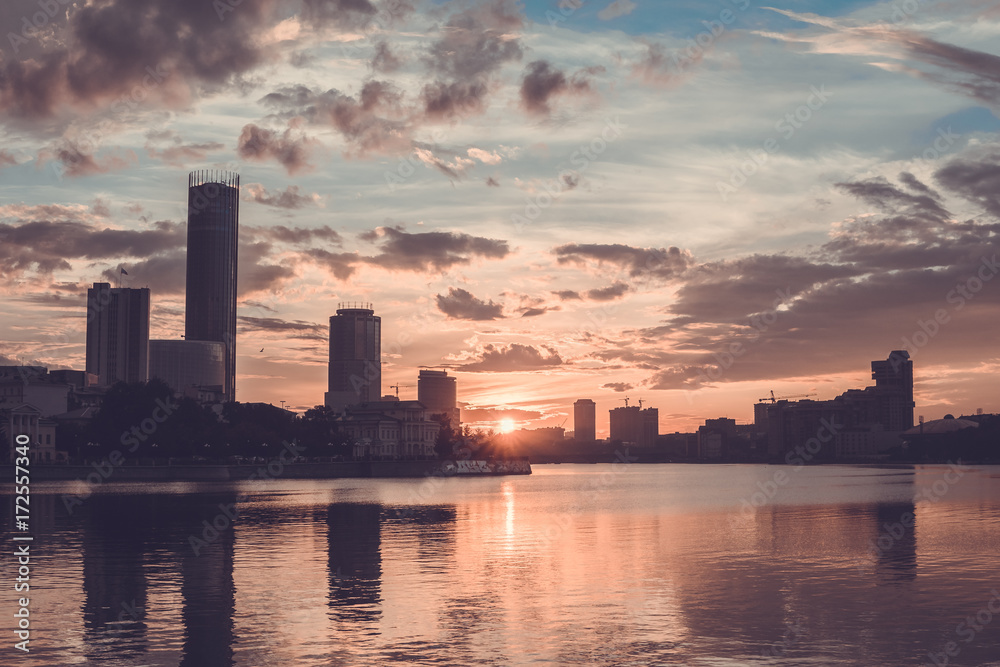 Yekaterinburg city center on sunset. City pond view, amazing clouds and sky. High buildings, skyscrapers on the embankment of the river Iset