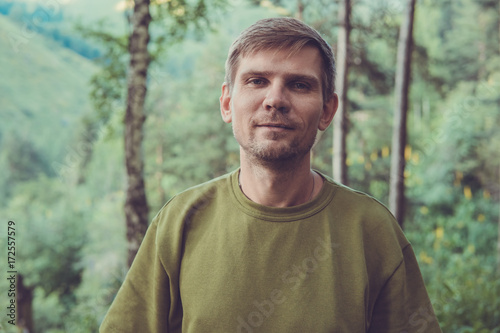 Young man portrait in a summer forest in the mountains