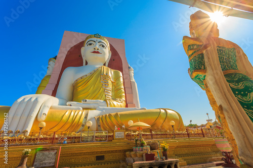 Illuminating Sunlight, Kyaik Pun Buddha the big Four Seated Buddha statues Shrine Sitting Back to Back of Four Directions on blue sky, Bago (Pegu), Myanmar. photo