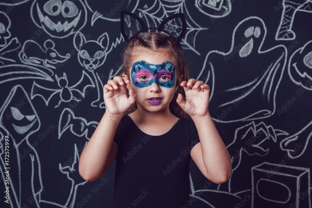 Girl in a cat costume on dark background with Halloween illustrations. Girl in a cat costume on dark background with Halloween illustrations.