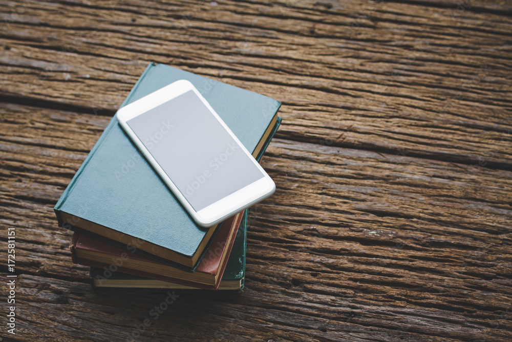 Fototapeta premium Book with smartphone on wood vintage tone