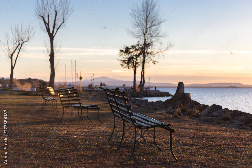 Sitting benches on a lake shore at sunset