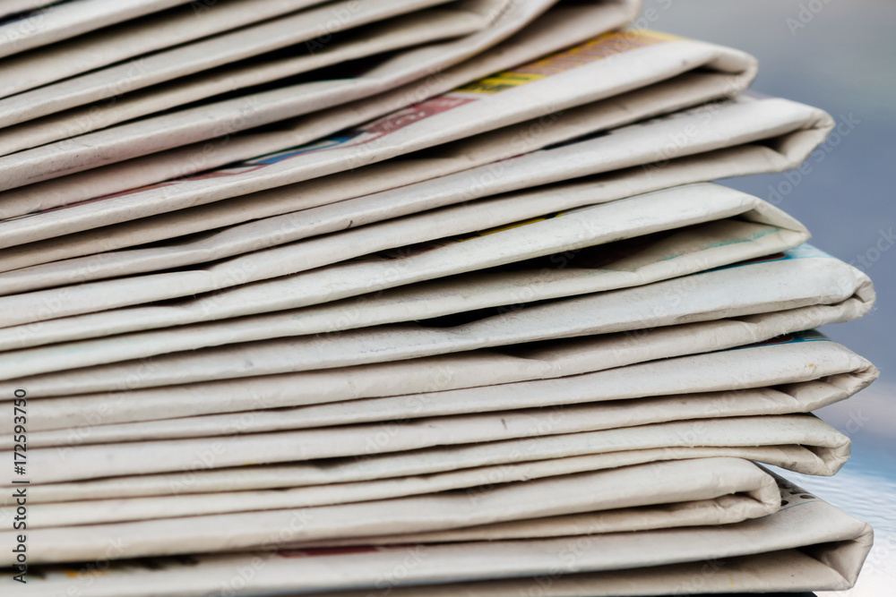 Time to read concept. Newspapers folded and stacked on the blue surface and blur background. Closeup, selective focus Time to read concept. Newspapers folded and stacked on the blue surface and blur background. Closeup, selective focus