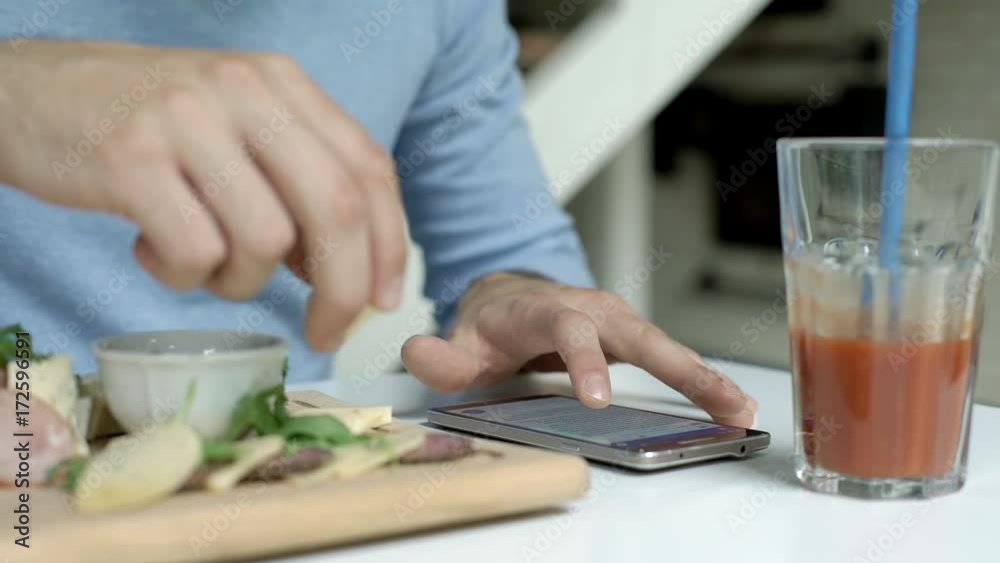 Man eating lunch and reading news on smartphone
Man eating lunch and reading news on smartphone