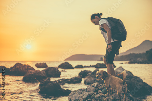 Woman with a dog hiking along the seashore