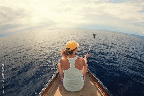 woman travels by sea making selfie sitting on stern of boat
