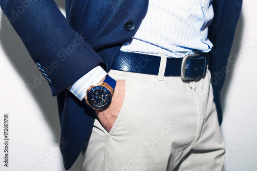 Closeup fashion image of luxury watch on wrist of man.body detail of a business man.Man's hand in a white shirt,blue jacket  in a pants pocket closeup. Tonal correction.Man posing in blue suit.