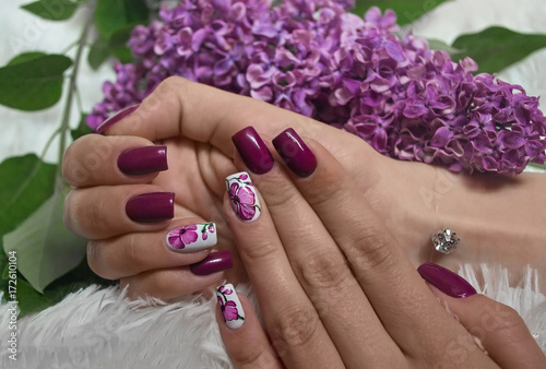 Photo manicure with orchids on the background of a lilac twig.Фотоподача маникюра с орхидеями на фоне веточки сирени.