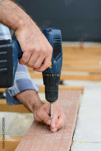 close up of manual worker hands screwing with cordless electric drill screwdriver