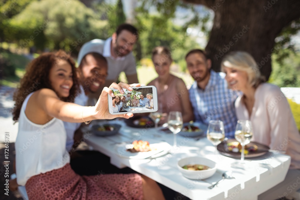 Friends taking selfie on mobile phone while having meal Friends taking selfie on mobile phone while having meal
