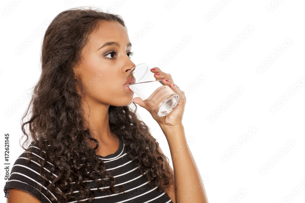 young beautiful african girl drinking water from a glass on white background young beautiful african girl drinking water from a glass on white background