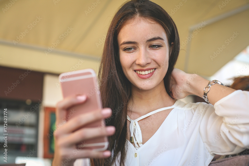 Young teenager girl making self picture in cafe. Teenager girl using smart phone.