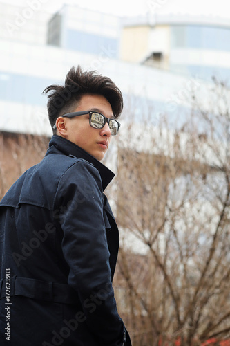 Asian young man in a coat on the street