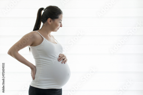 Fototapeta Naklejka Na Ścianę i Meble -  Young beautiful pregnant woman touching her belly with hands