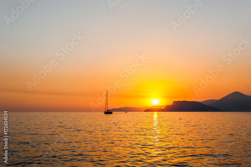 Tranquil nature scene of sailing boat in the ocean at sunset  © vladteodor