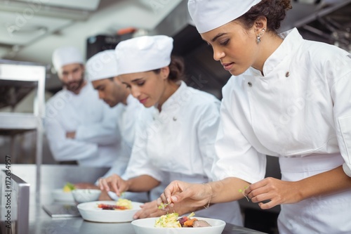 Female chef garnishing food in kitchen photo