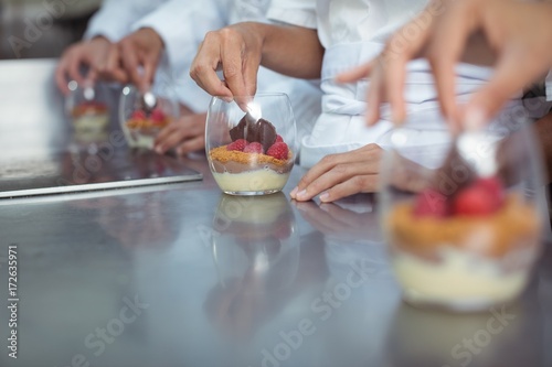 Chefs finishing dessert in glass at restaurant