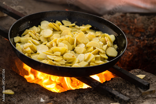 Potatoes fried in a frying pan in the open air