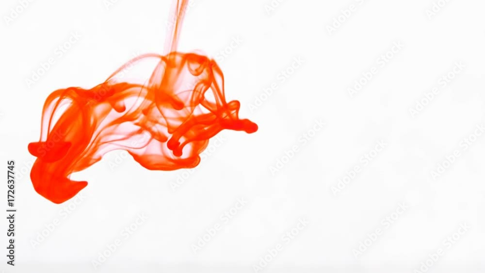 Red and green ink dropped into water against a white background. 