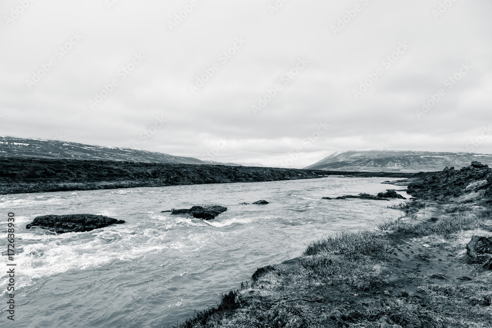 Water of stormy mountain river from waterfall - beautiful part of stony rocky desert landscape of Iceland. Toned Water of stormy mountain river from waterfall - beautiful part of stony rocky desert landscape of Iceland. Toned