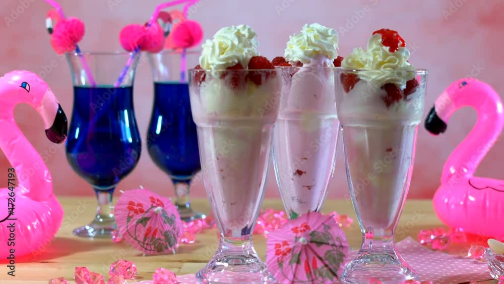 4k Pink Flamingo theme Summer party table with ice cream sundaes closeup, adding strawberry topping sauce. 4k Pink Flamingo theme Summer party table with ice cream sundaes closeup, adding strawberry topping sauce.