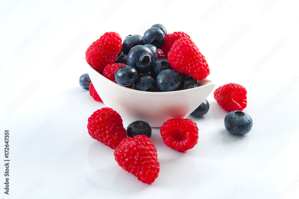 Fresh berry fruits and healthy eating concept with mixed blueberries and raspberries in a heart shaped bowl Fresh berry fruits and healthy eating concept with mixed blueberries and raspberries in a heart shaped bowl