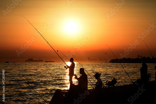 Silhouettes of many fishermen fishing in sea