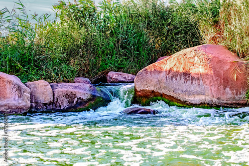 A beautifull view of mini waterfall on Kamenka river, Tokovskoe settlement, Apostolove Raion, Dnipropetrovsk Oblast, Ukraine. Water running through boulders. photo