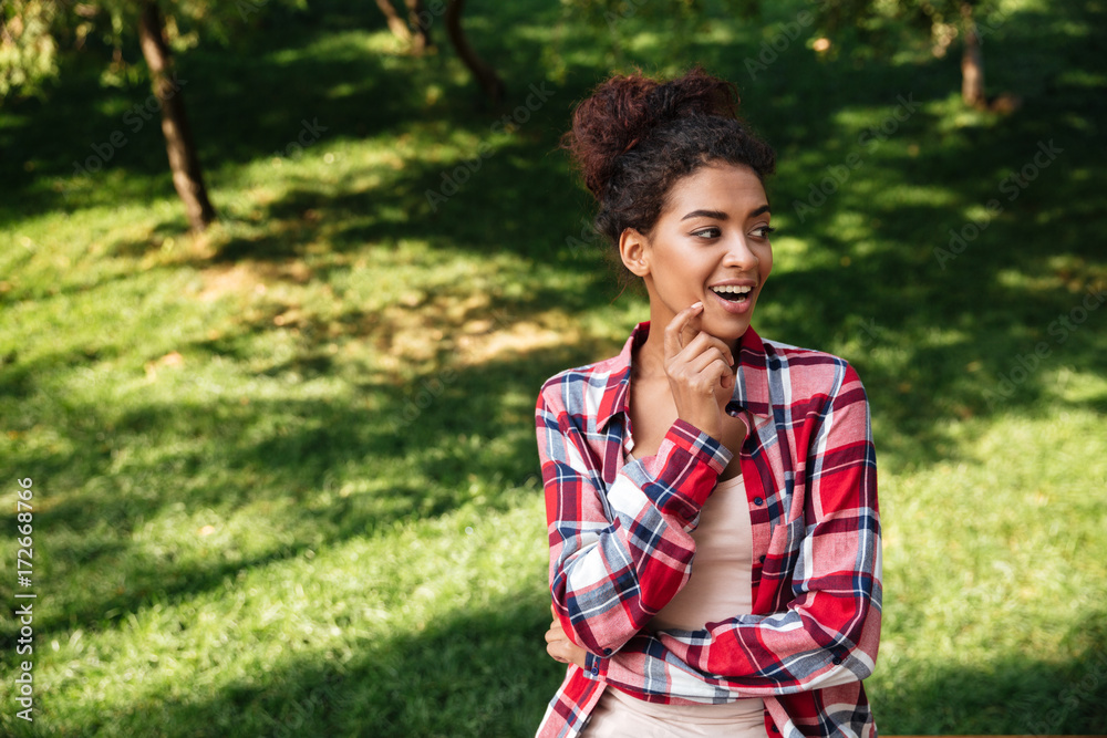 Pretty young african woman sitting outdoors in park Pretty young african woman sitting outdoors in park