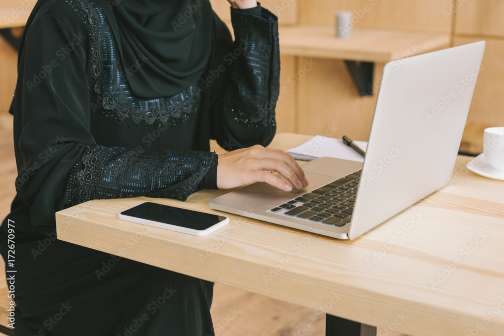 muslim woman using laptop in cafe muslim woman using laptop in cafe