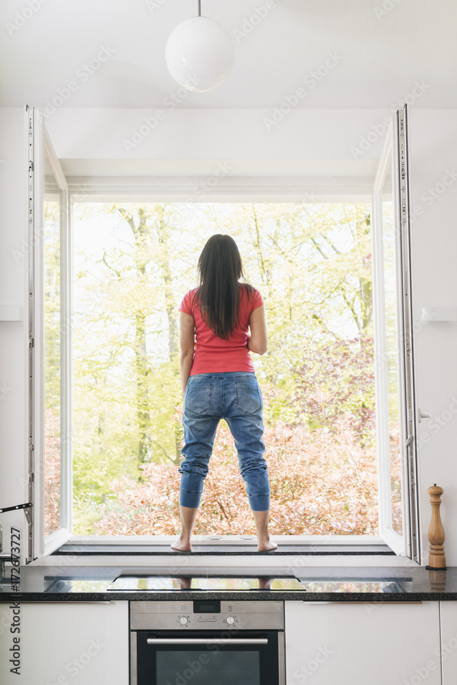 Woman standing in kitchen on windowsill