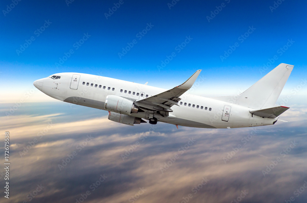 Passenger airplane flies on a flight level against a background of clouds and a blue sky Passenger airplane flies on a flight level against a background of clouds and a blue sky