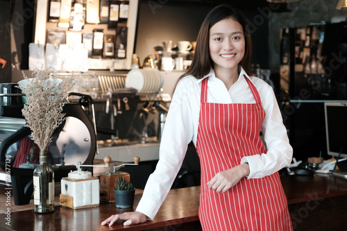 Young asian women Barista standing with smiling face in font of cafe counter background, small business owner, food and drink industry concept